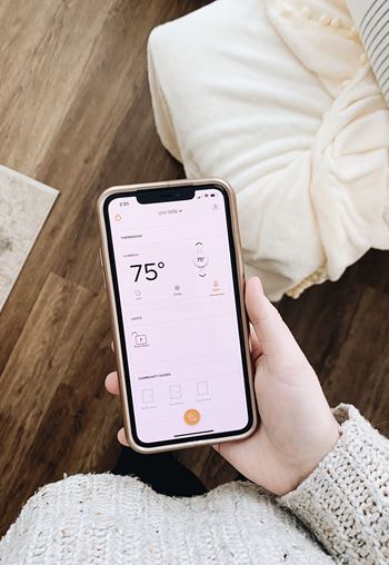 Person holding a phone with a temperature of 75 degrees displayed on the screen